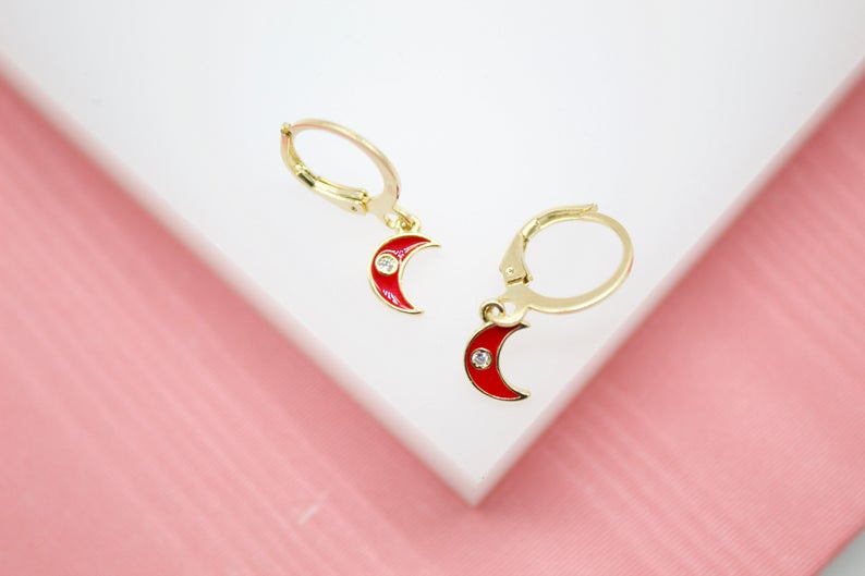 A pair of gold hoop earrings features dangling red crescent moon charms with sparkling crystal accents.