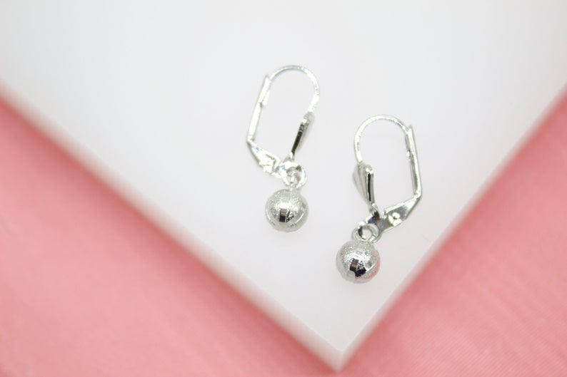 A pair of elegant sterling silver leverback earrings dangle against a soft pink and white background.