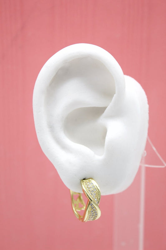 A white mannequin ear displays a sparkling gold twist hoop earring against a pink background.