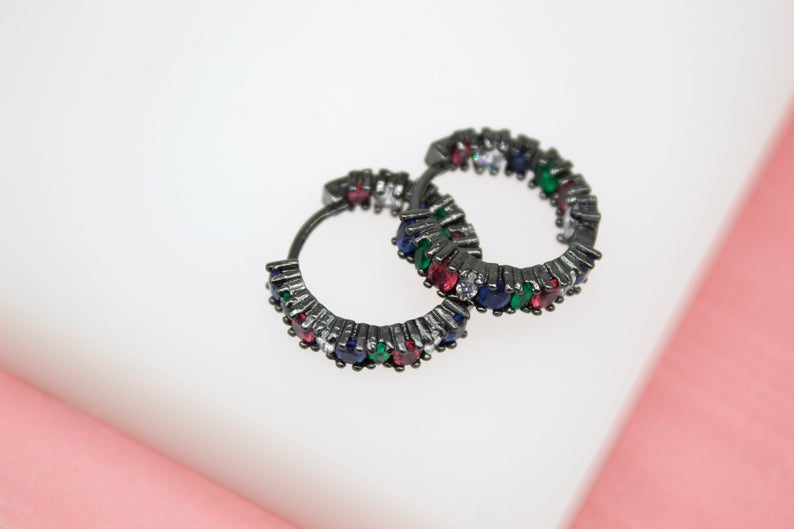 A pair of black rhodium-plated hoop earrings features colorful multi-gemstone pave settings against a neutral background.