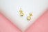 A pair of gold ball stud earrings featuring sparkling inset crystals rests on a light background.