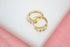 Two shimmering gold hoop earrings featuring embedded sparkling cubic zirconia stones rest on a white surface.