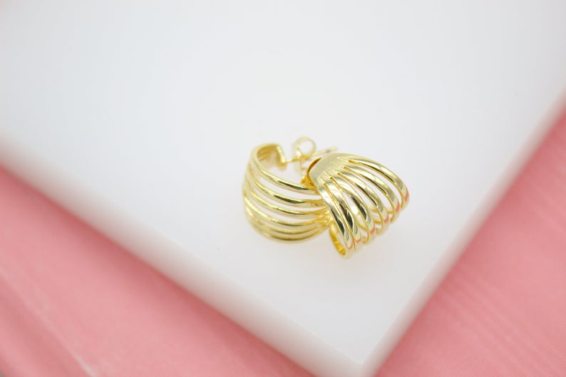 A pair of multi-strand gold hoop earrings rests on a clean white surface.