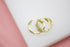 Two elegant gold huggie hoop earrings featuring geometric hexagonal designs encrusted with sparkling cubic zirconia stones rest on a soft white surface.