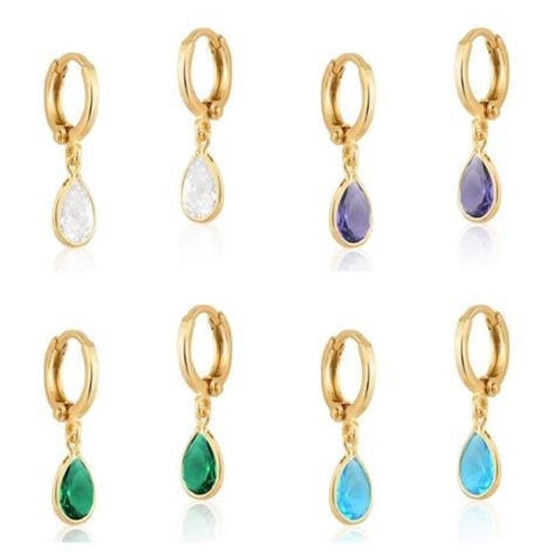 A collection of gold-plated huggie hoop earrings featuring dangling teardrop cubic zirconia stones in various colors.