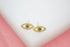 A pair of gold evil eye stud earrings features sparkling pave diamonds and vibrant red gemstone centers against a neutral white backdrop.