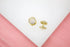A pair of gold pave-set CZ dome earrings rests on a white and pink surface.
