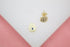 A pair of gold Hamsa hand stud earrings featuring sparkling pave crystals and a central blue stone rest on a white surface.