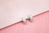 A pair of sparkling pavé-set silver hoop earrings rests on a soft pink background.