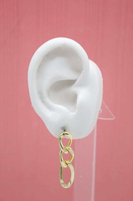 A white mannequin ear displays a polished gold chain-link dangle earring against a solid pink backdrop.