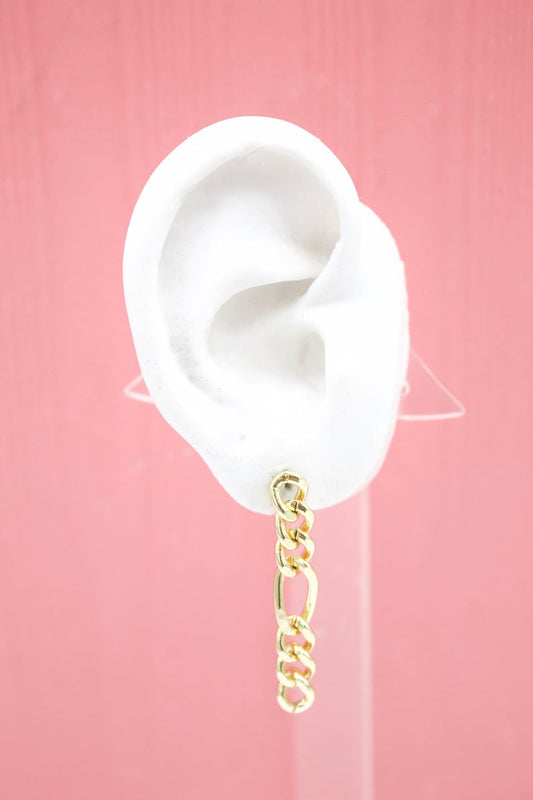 A white mannequin ear displays a dangling gold chain link earring against a pink background.
