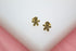 A pair of gold gingerbread man stud earrings featuring sparkling pave crystals rests on a white display stand.