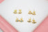 Four pairs of gold evil eye stud earrings with colorful enamel centers display on a white surface.