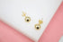 A pair of polished gold ball stud earrings rests against a white and pink background.