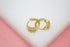 A pair of sparkling gold hoop earrings with crystal embellishments rest on a soft white surface.