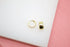 A pair of sleek gold huggie hoop earrings rests on a white display surface.