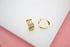 A pair of polished gold multi-row huggie hoop earrings rests on a clean white surface.