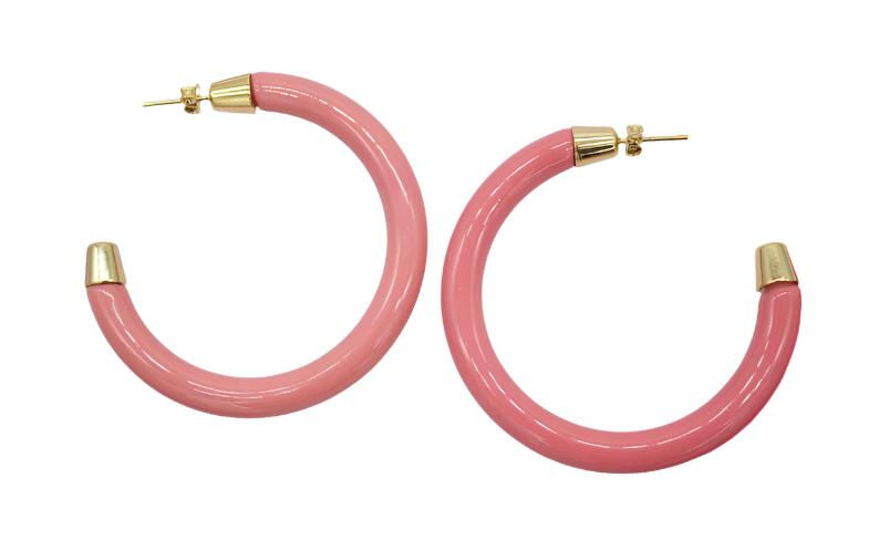 A pair of chunky pink hoop earrings with gold-plated caps rests against a plain white background.