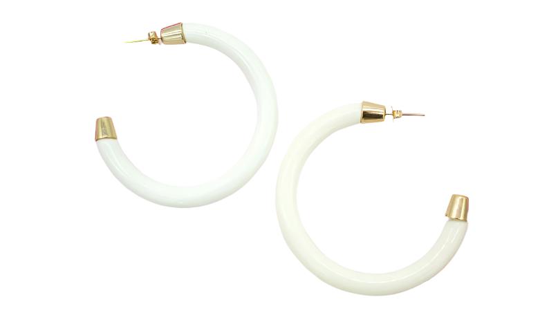 A pair of white hoop earrings features polished gold caps at the post and tip against a plain white background.