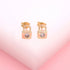 A pair of gold padlock stud earrings sparkle with tiny embedded crystals against a soft pink and white background.