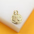 A gold best friends broken heart pendant rests on a white surface against an orange background.
