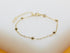 A delicate gold chain bracelet features evenly spaced shiny bead charms against a neutral background.
