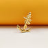 A polished gold anchor pendant stands upright against a contrasting orange and white background.