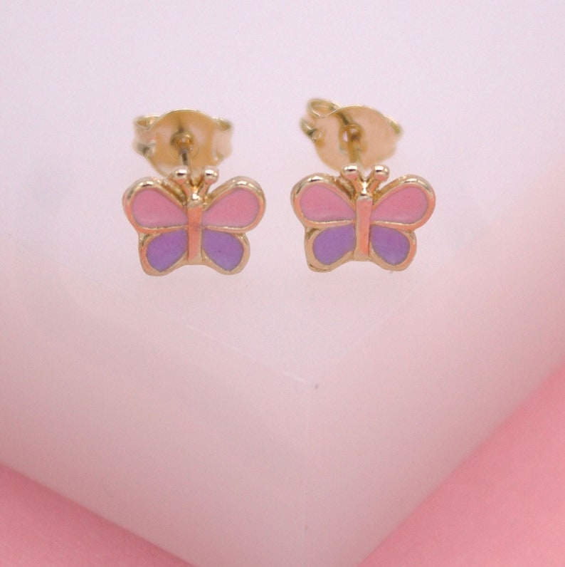 A pair of gold butterfly stud earrings feature vibrant pink and purple enamel wings.