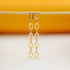 Two long, gold-plated chain drop earrings hang gracefully from a horizontal wooden stick against a bright yellow and white background.