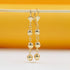 A pair of elegant gold-plated dangle earrings featuring graduated spherical beads hang gracefully against a warm yellow and white background.