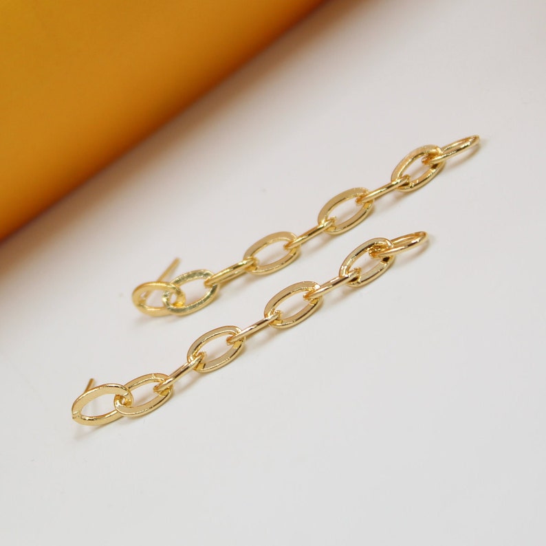 A pair of elegant gold chain link drop earrings rests on a clean white surface.