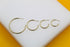 Four graduated gold hoop earrings are displayed in a row on a white and yellow display stand.