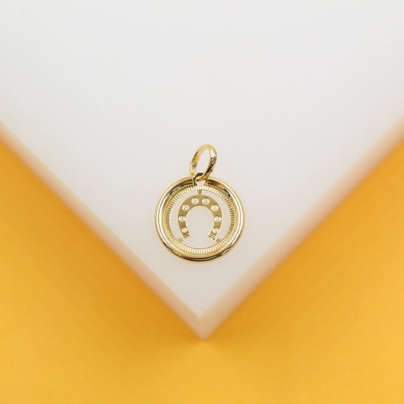 A gold horseshoe charm sits centered on a white and yellow display surface.
