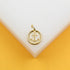 A gold anchor pendant rests on a white and yellow display stand.