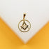 A polished gold Masonic pendant featuring the square and compasses symbol with the letter G rests on a white display surface.