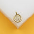 A polished gold Saint Benedict medal pendant rests on a clean white and yellow display surface.