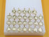 A collection of gold initial letter pendants, encrusted with rhinestones, are arranged in alphabetical order on a white display block.
