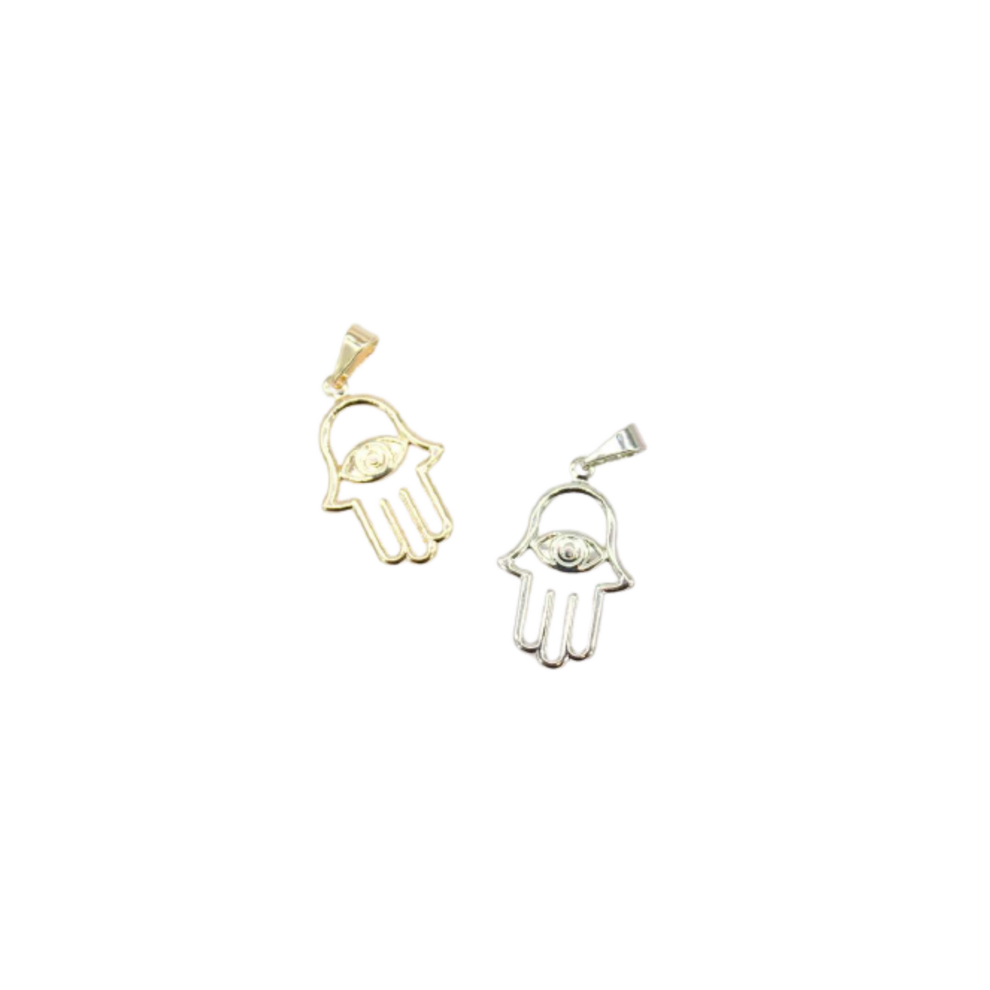 Two hamsa hand pendants featuring evil eye designs lie side by side, showcasing a gold version on the left and a silver one on the right against a plain white background.