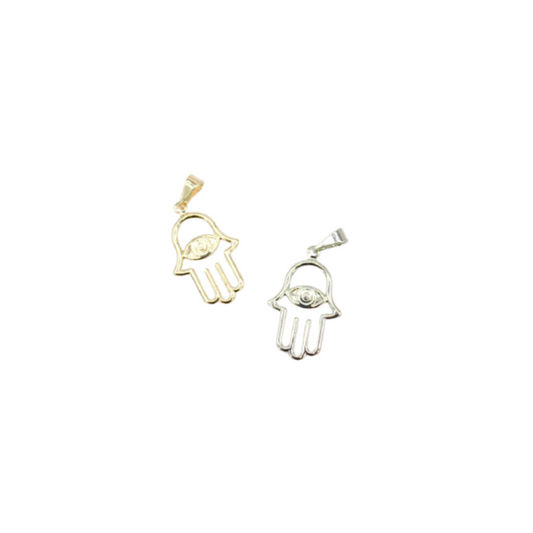 Two hamsa hand pendants featuring evil eye designs lie side by side, showcasing a gold version on the left and a silver one on the right against a plain white background.